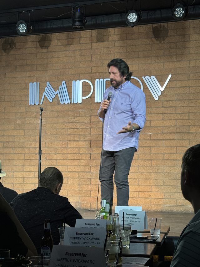 Dennis F. Bonilla performing stand-up on stage at the Improv
