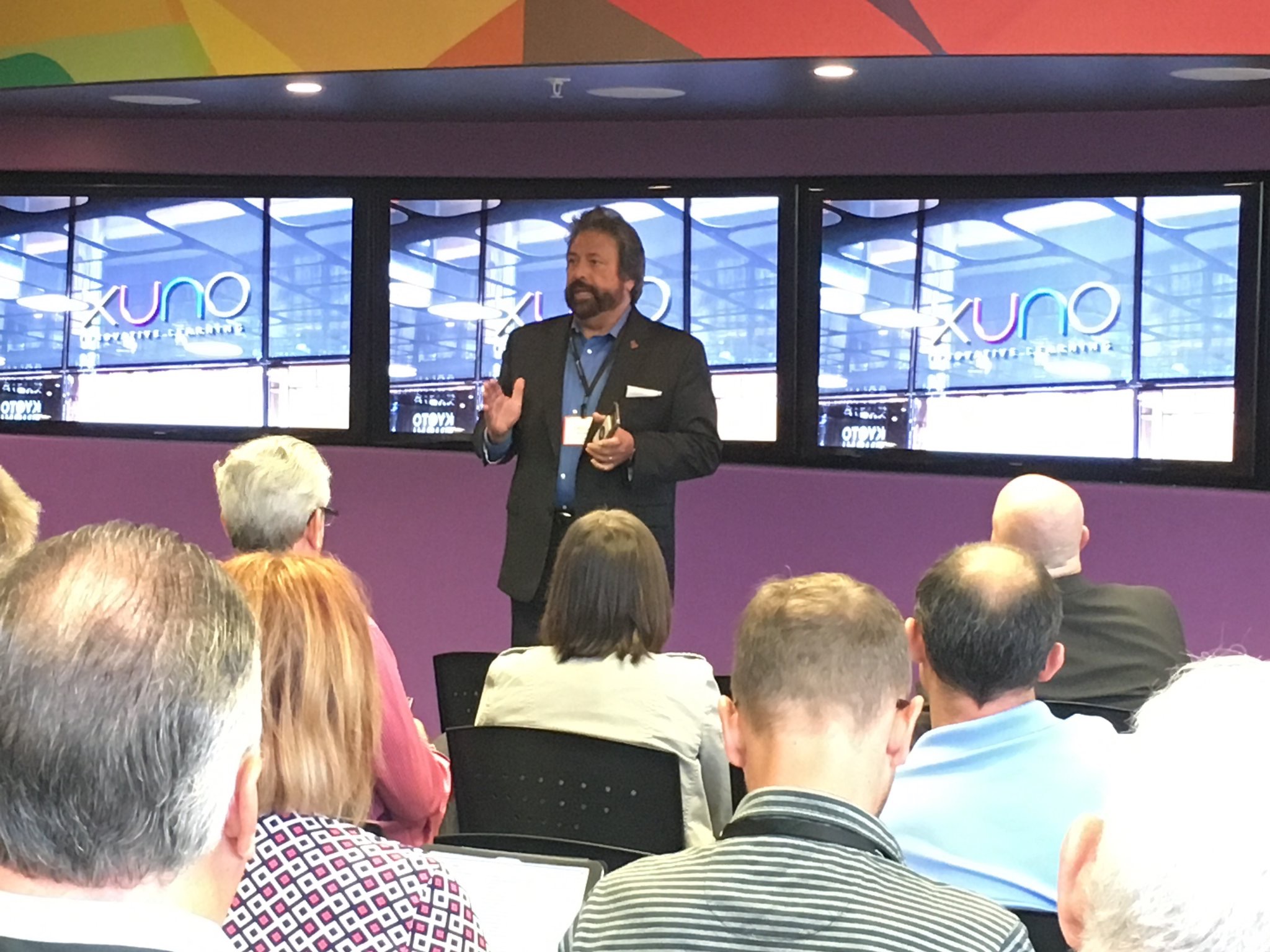 Dennis Bonilla speaking on stage at an XUNO adaptive learning event