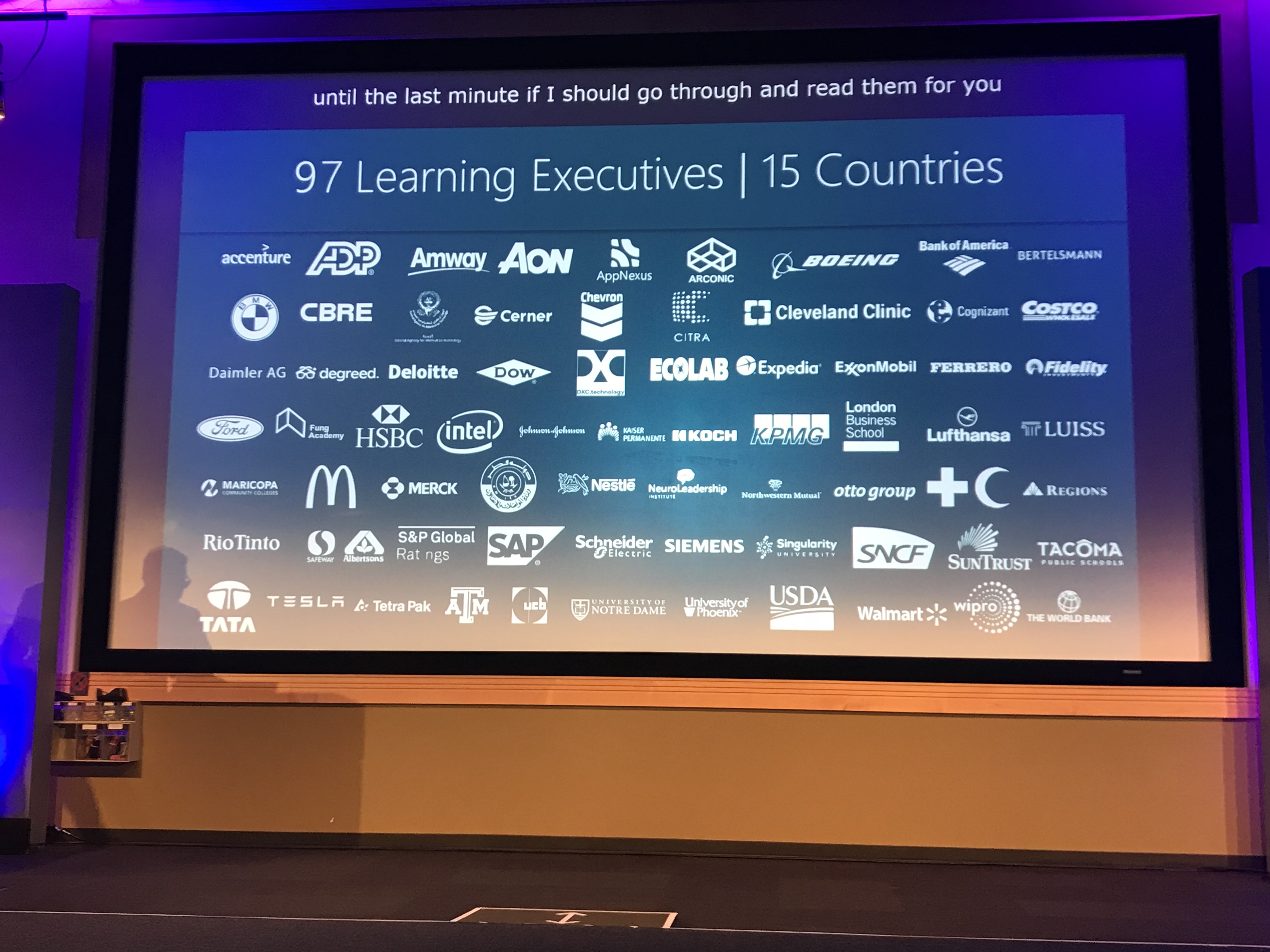 Conference screen listing 97 learning executives from 15 countries