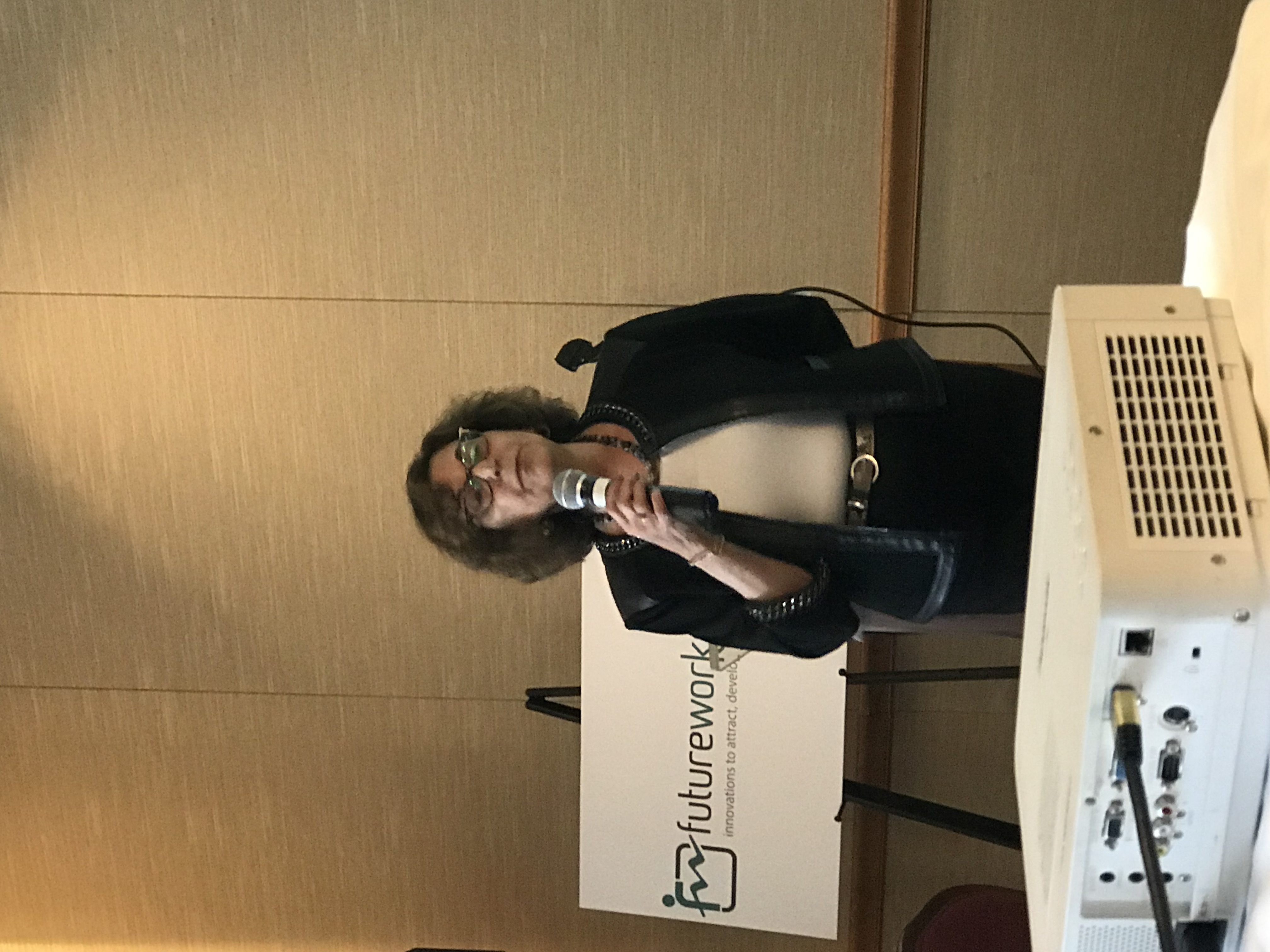 Speaker presenting in front of a Futurework conference sign