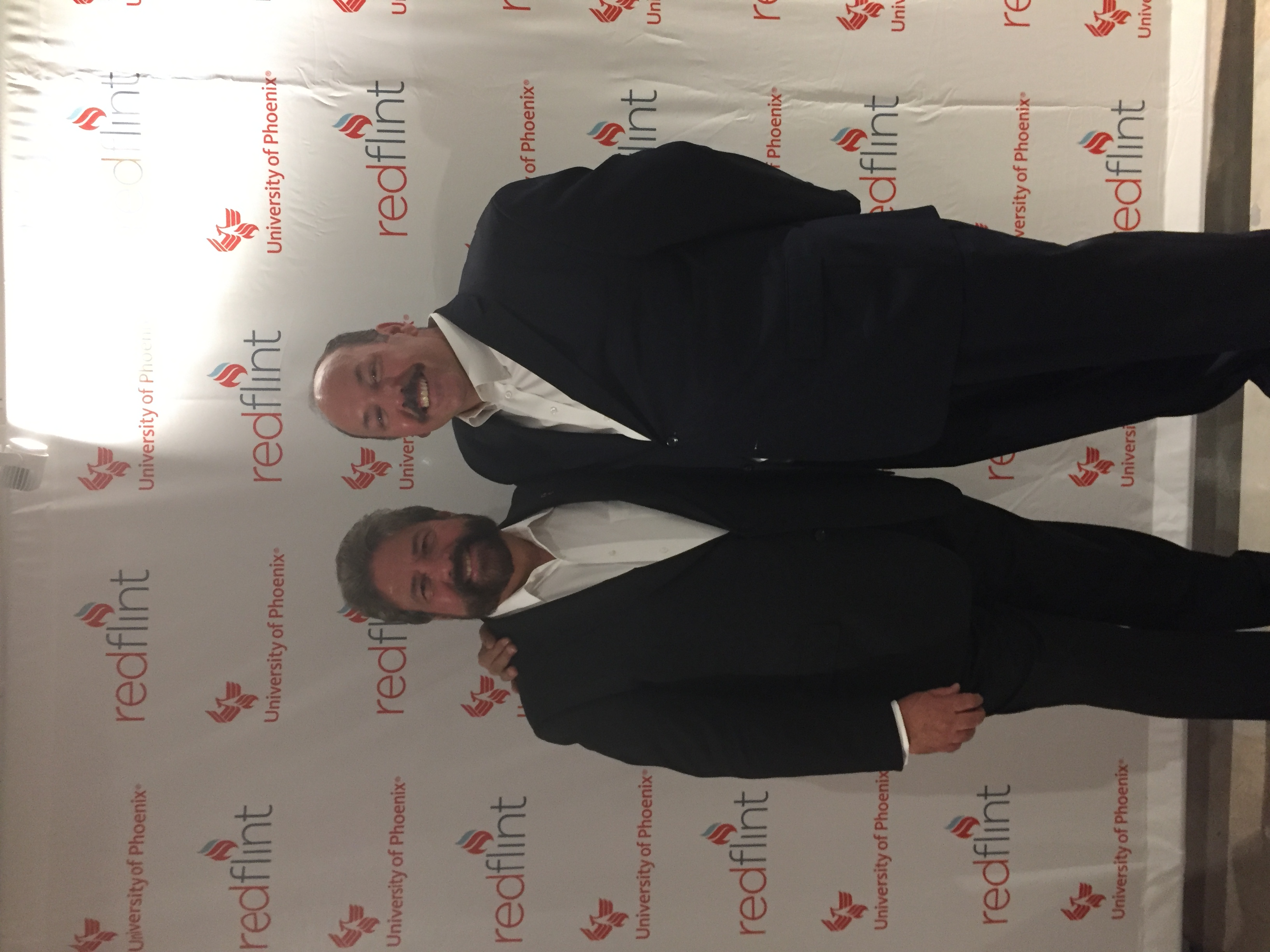 Dennis Bonilla with a colleague at a RedFlint and University of Phoenix event backdrop