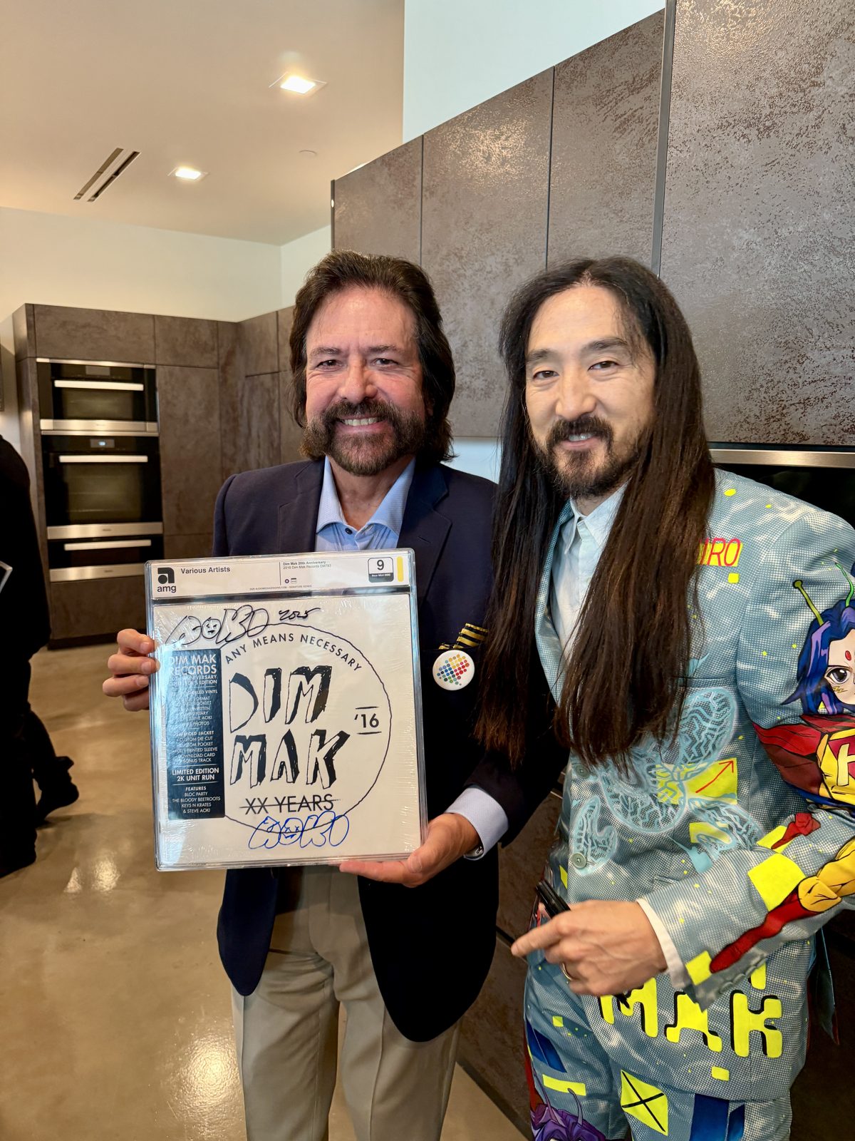 Dennis Bonilla with Steve Aoki holding a signed Dim Mak Records anniversary vinyl