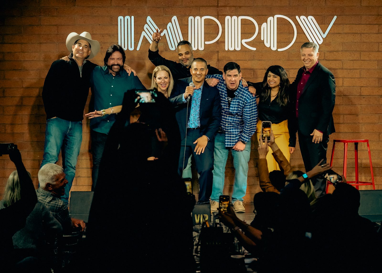 Dennis Bonilla on stage with a group of comedians and colleagues at an Improv comedy club